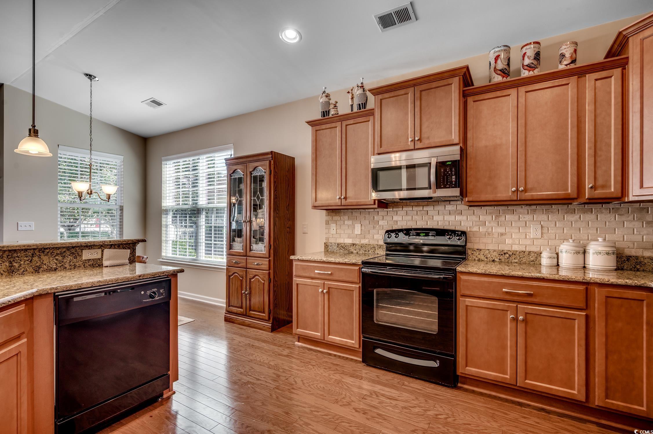 202 Fox Den Drive Murrells Inlet, SC 29576 - Photo 18 of 35 Kitchen featuring black appliances, backsplash, light stone countertops, light wood-style floors, and hanging light fixtures