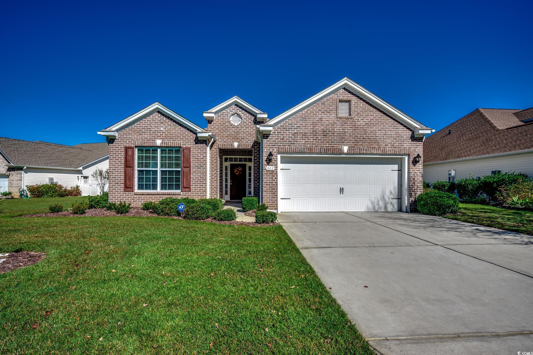 202 Fox Den Drive Murrells Inlet, SC 29576 - Photo 4 of 35 View of front facade featuring driveway, a front lawn, brick siding, and a garage