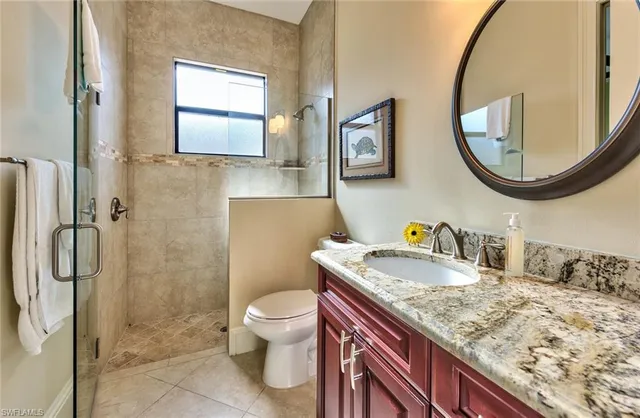 a bathroom with a granite countertop sink mirror vanity and toilet