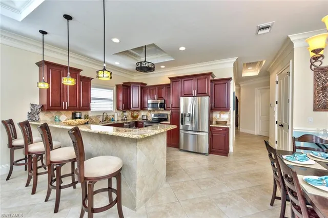 a kitchen with stainless steel appliances kitchen island granite countertop a table chairs and a refrigerator