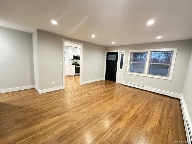 a view of empty room with wooden floor and window
