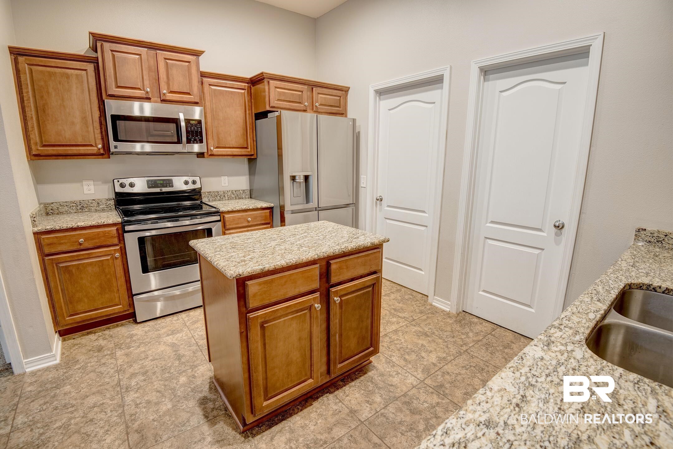 15345 Fremont Court Foley, AL 36535 - Photo 15 of 35 Kitchen with light stone countertops, stainless steel appliances, sink, light tile patterned floors, and a center island