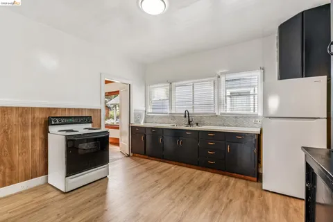 a kitchen with stainless steel appliances granite countertop a stove a sink dishwasher a refrigerator and a stove with wooden floors