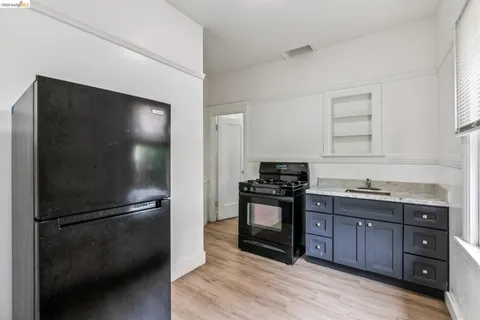 a kitchen with granite countertop a refrigerator and a stove top oven