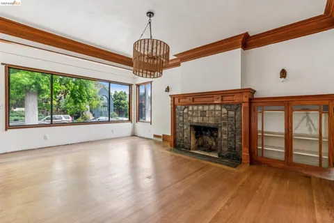 a view of an empty room with wooden floor fireplace and a window