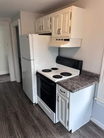 a kitchen with granite countertop a refrigerator a stove a sink and cabinets