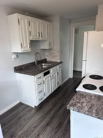 a kitchen with granite countertop a sink a stove and cabinets