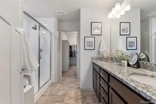 a bathroom with a granite countertop sink a mirror and shower