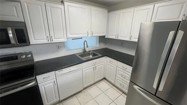 a kitchen with white cabinets and refrigerator
