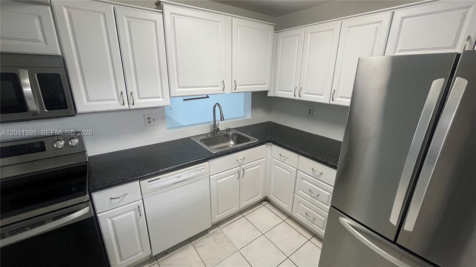 a kitchen with white cabinets and refrigerator
