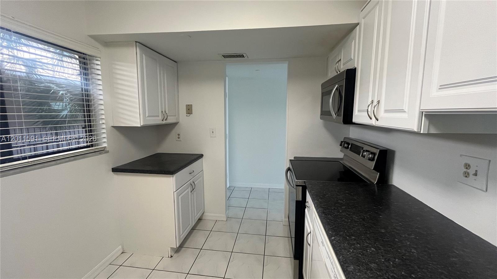 8540 Southwest 133rd Avenue Road, Unit 316 Miami, FL 33183 - Photo 4 of 18 a kitchen with a sink a stove and cabinets