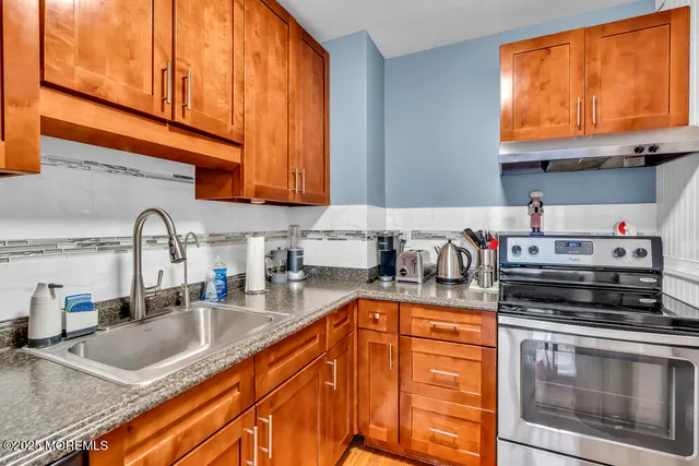 a kitchen with stainless steel appliances granite countertop a sink a stove and cabinets