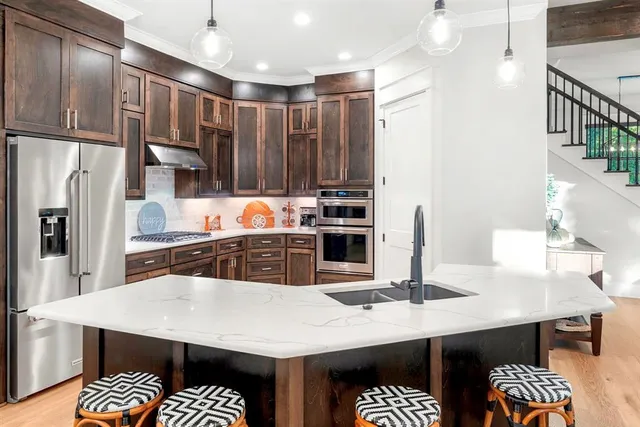 a kitchen with stainless steel appliances kitchen island granite countertop a table chairs and a refrigerator