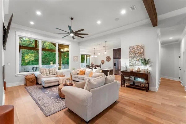 a kitchen with stainless steel appliances a stove a refrigerator a sink a dining table and chairs with wooden floor