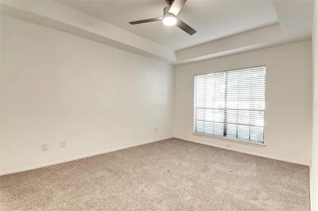 an empty room with a window and ceiling fan