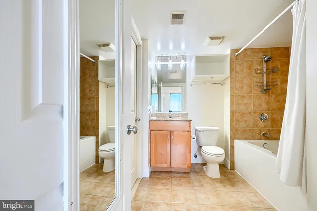 a bathroom with a granite countertop toilet a sink a mirror and a shower