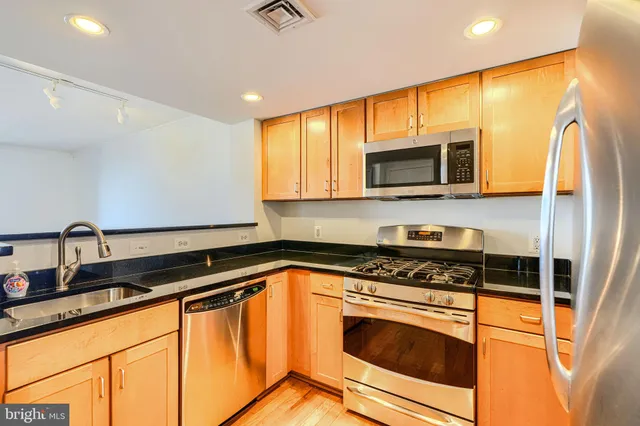 a kitchen with stainless steel appliances granite countertop a stove a sink and a microwave