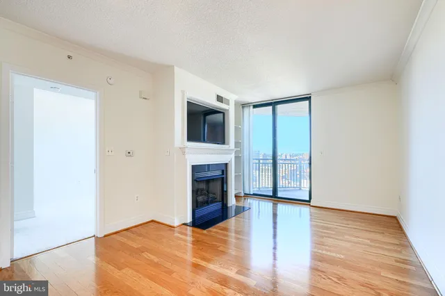a view of an empty room with wooden floor fireplace and a window