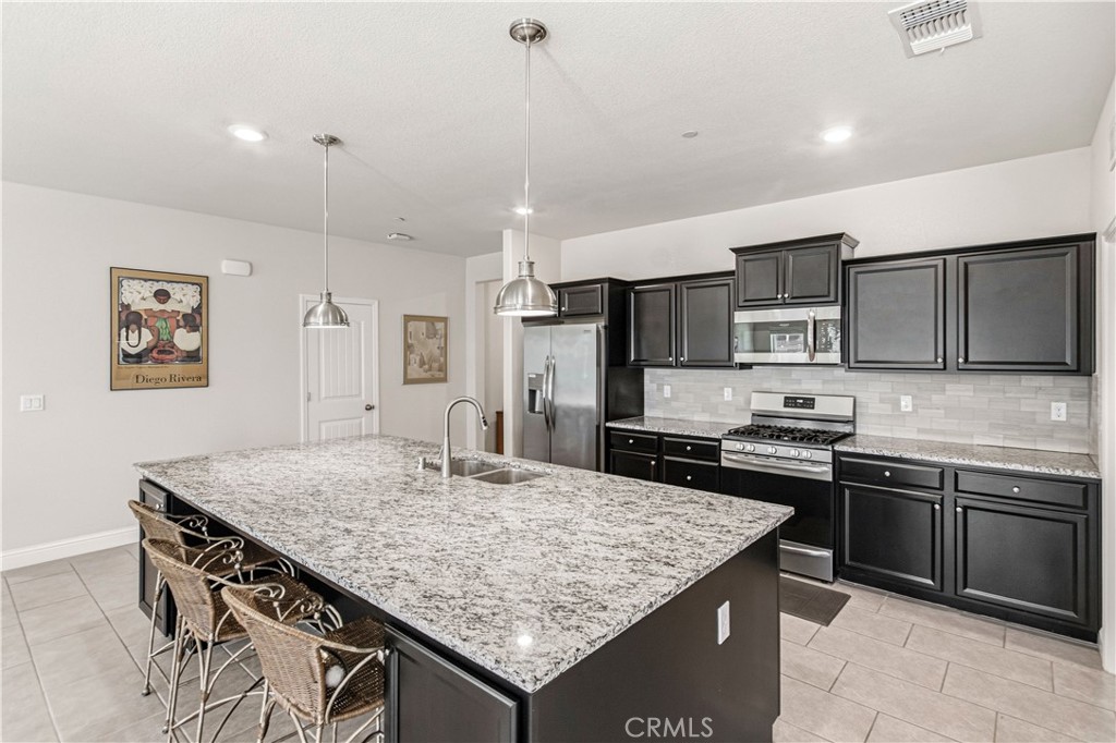 3716 Magellan Drive Merced, CA 95340 - Photo 5 of 27 a kitchen with stainless steel appliances granite countertop a kitchen island a cabinets and wooden floor