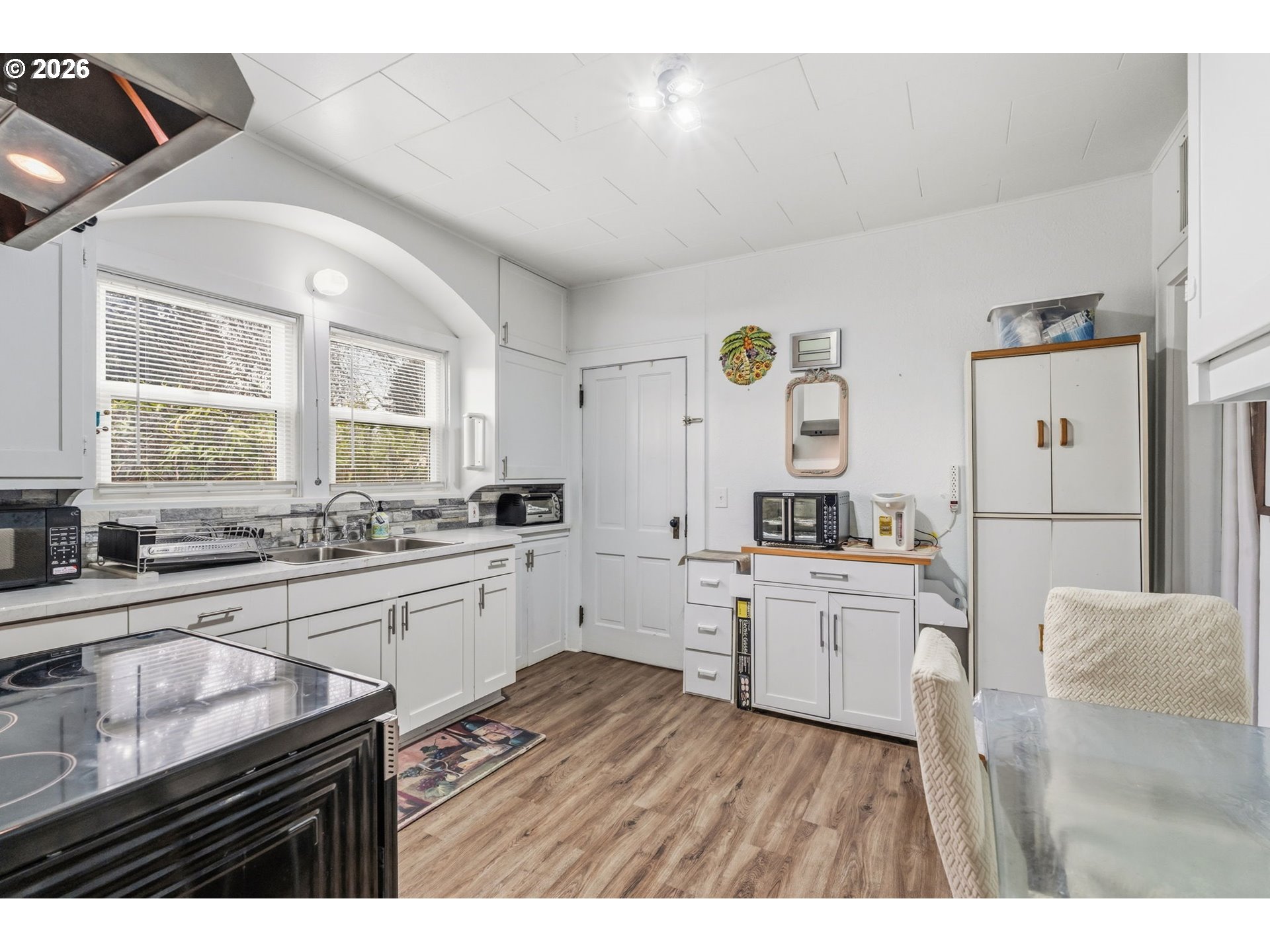3315 West 18th Avenue Eugene, OR 97402 - Photo 5 of 26 a kitchen with granite countertop a sink cabinets wooden floor and stainless steel appliances
