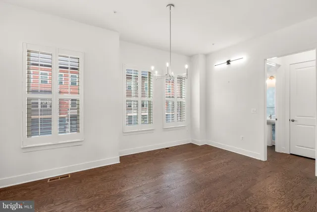 a large white kitchen with a refrigerator a sink dishwasher a stove and a dining table with wooden floor