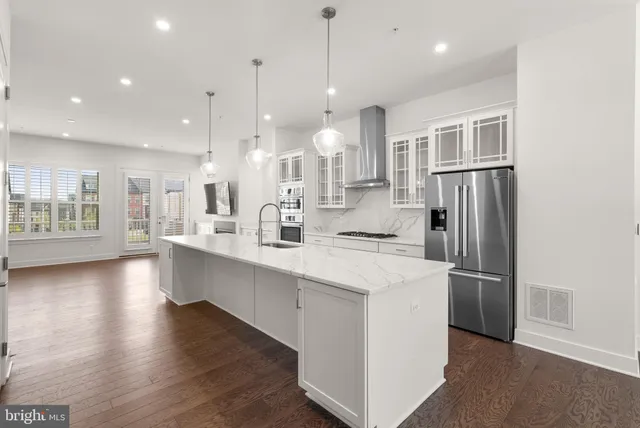 a large kitchen with stainless steel appliances kitchen island a large counter top and a wooden floors