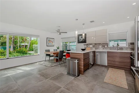 a open kitchen with stainless steel appliances kitchen island granite countertop a table chairs and a refrigerator