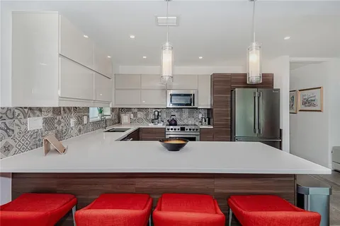 a kitchen with stainless steel appliances a refrigerator a sink a stove a center island and chairs