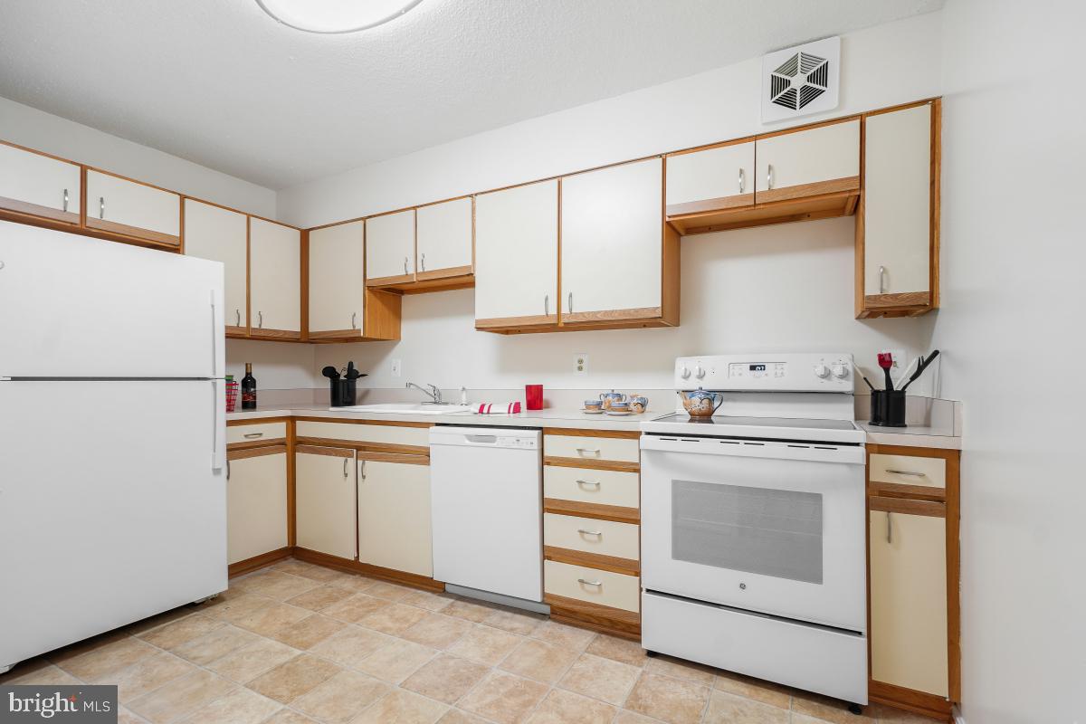 15107 Interlachen Drive, Unit 2321 Silver Spring, MD 20906 - Photo 18 of 35 a kitchen with granite countertop white cabinets and white appliances