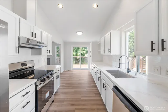 a large kitchen with stainless steel appliances granite countertop a lot of counter space and wooden floors