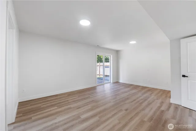 a view of an empty room with wooden floor and windows