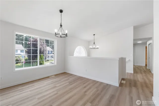 a view of a room with wooden floor chandeliers and kitchen view