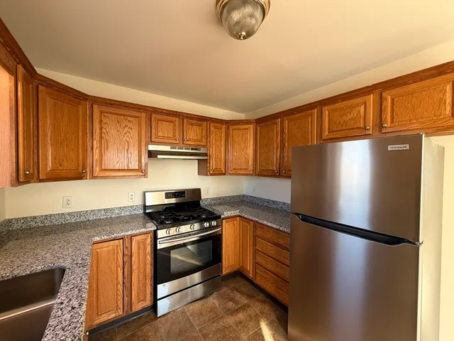 a kitchen with granite countertop stainless steel appliances a refrigerator a stove top oven and granite countertops