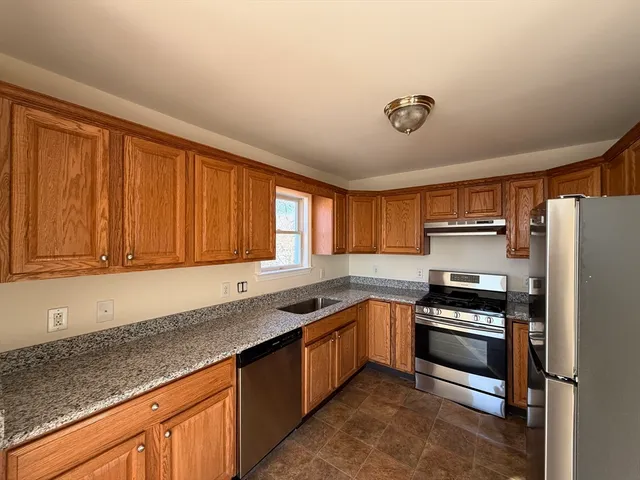 a kitchen with stainless steel appliances granite countertop a stove a sink and a refrigerator