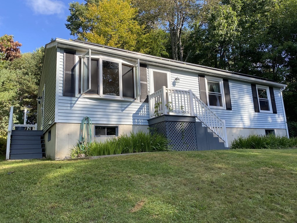 a front view of house with yard and trees in the background