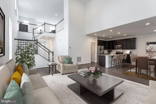a living room with furniture kitchen view and a wooden floor