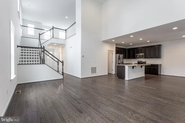 a large white kitchen with stainless steel appliances kitchen island granite countertop a stove a sink and a microwave