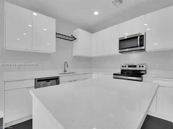 a kitchen with stainless steel appliances a stove a microwave and white cabinets