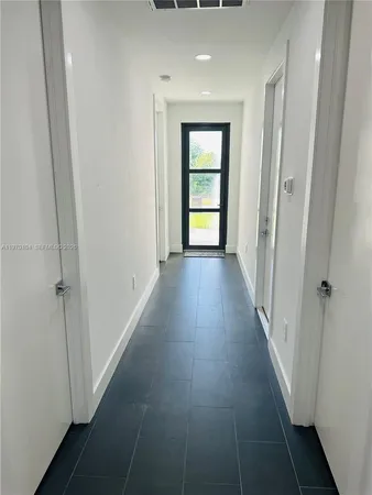 a view of a hallway with wooden floor and a living room