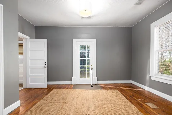 a view of an empty room with wooden floor and a window