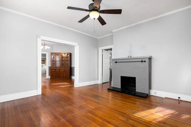 a view of an empty room with wooden floor fireplace and a window
