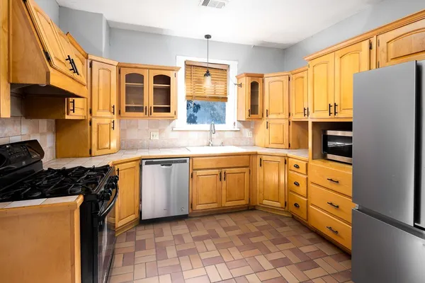 a kitchen with stainless steel appliances granite countertop a refrigerator a stove and a sink