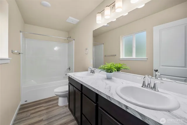 a bathroom with a granite countertop sink a toilet a mirror a bathtub and shower