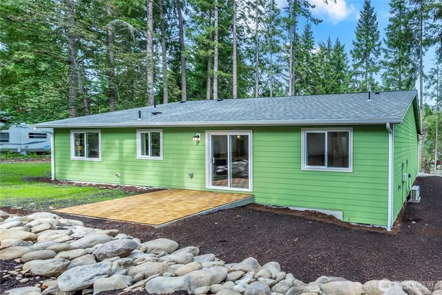 a view of a brick house with a yard plants and large tree