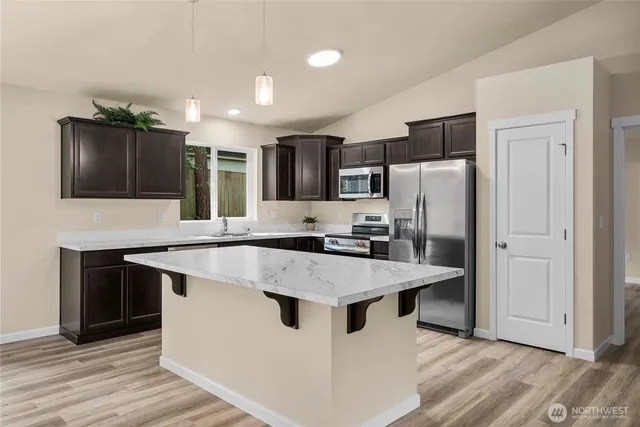 a kitchen with stainless steel appliances kitchen island a refrigerator sink and cabinets
