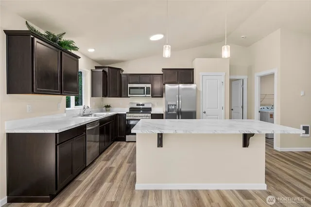 a kitchen with kitchen island stainless steel appliances a sink stove and refrigerator