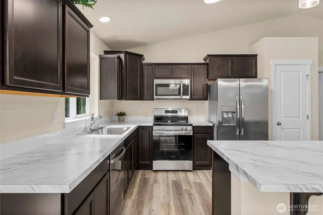 a kitchen with stainless steel appliances granite countertop a sink stove refrigerator and cabinets
