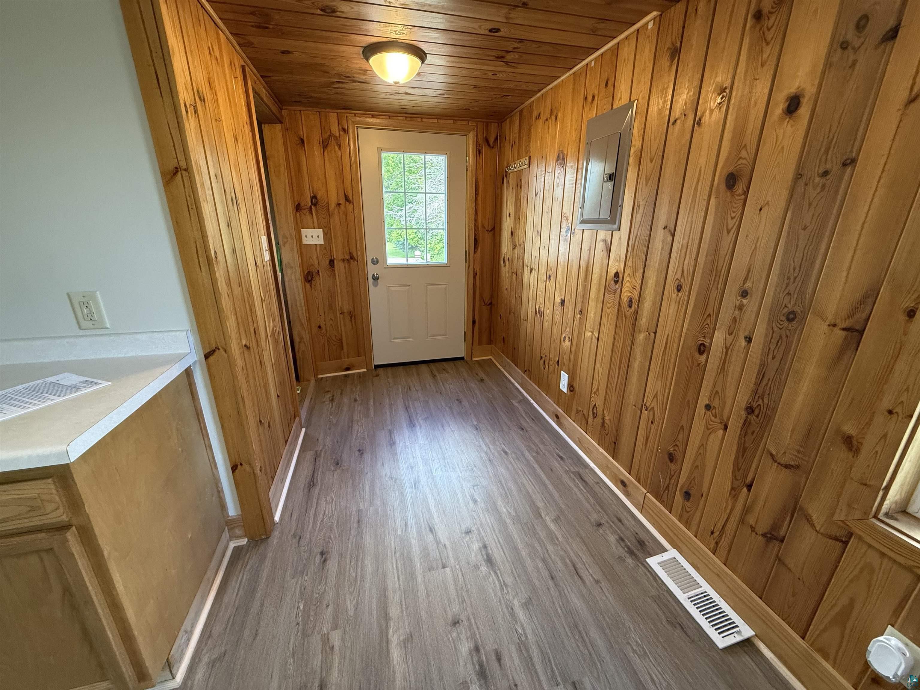 3841 Haines Road Hermantown, MN 55811 - Photo 2 of 11 Entryway featuring wood-paneled walls and ceiling, wood-finish flooring, and a white exterior door with glass inserts