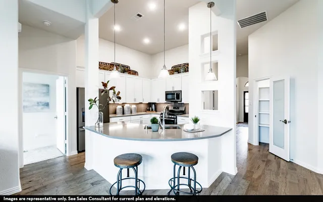 a kitchen with stainless steel appliances granite countertop a kitchen island and chairs in it