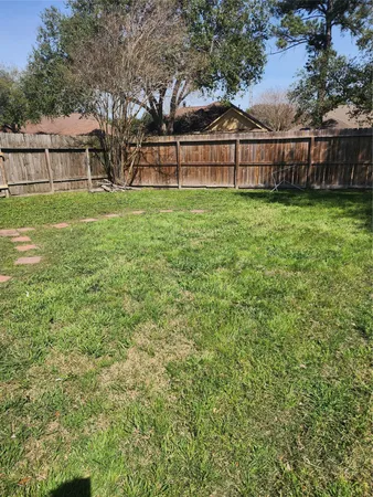 a view of a yard with large trees and wooden fence